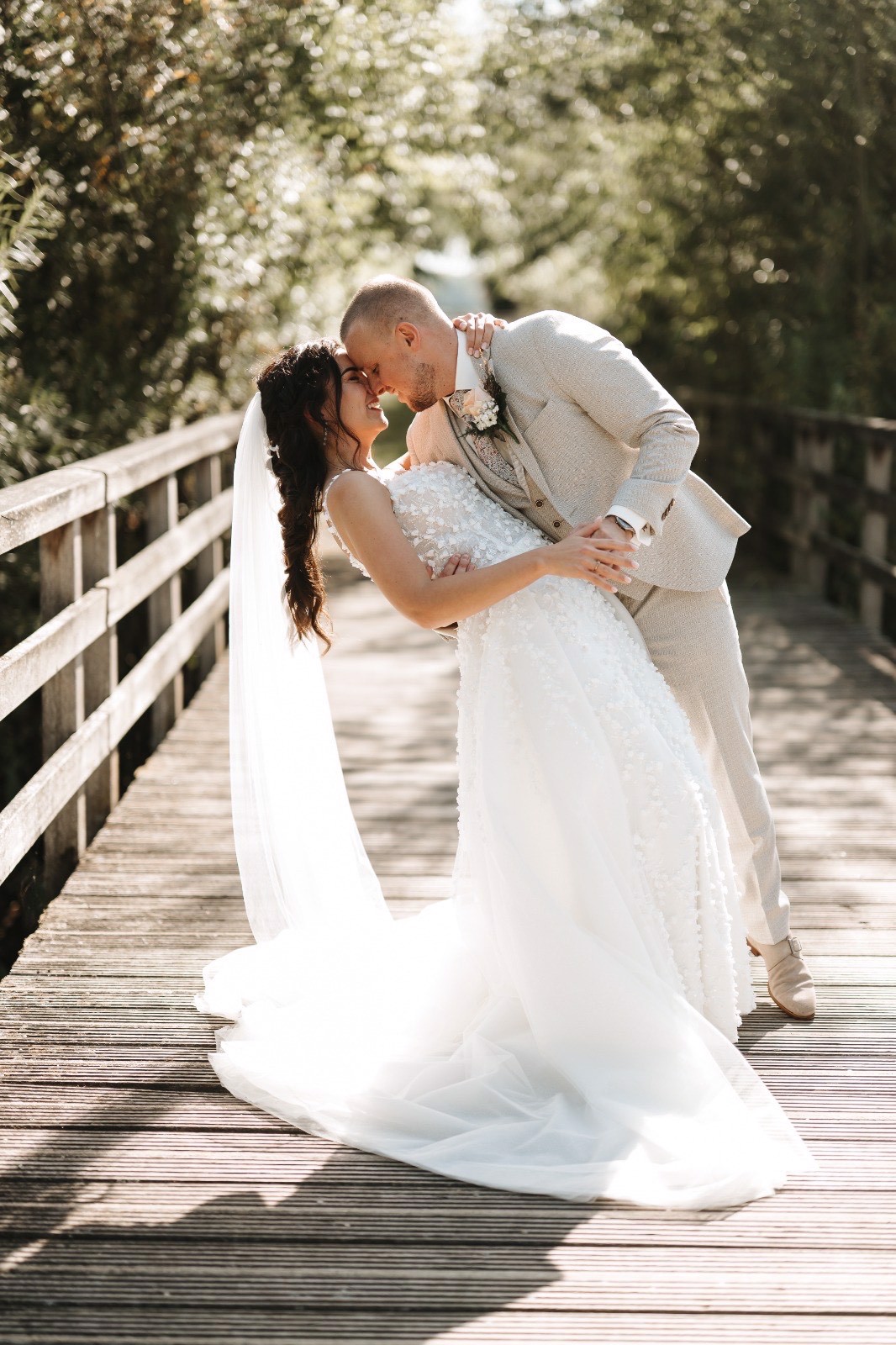 Real bride Femke en haar partner in dip-pose op een brug, met sluier en 3D-bloemenjurk.